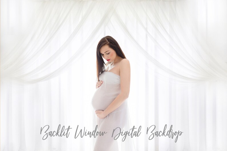 May include: A pregnant woman stands in front of a white sheer curtain backdrop. The curtains are draped in a way that creates a soft, ethereal look. The woman is wearing a white sheer dress and is holding her belly.