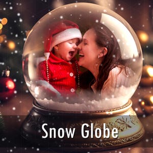Puede incluir: Una bola de nieve de cristal con una base que presenta patrones de hojas en relieve y el texto Snow Globe. Dentro de la esfera, un niño con gorro y chaqueta de Papá Noel ríe junto a un adulto, rodeados de partículas de nieve y luz cálida.