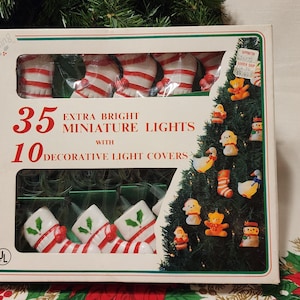 May include: A box of Christmas lights with 35 miniature lights and 10 decorative light covers. The box features images of stockings and a Christmas tree decorated with ornaments. The text on the box reads "Extra Bright Miniature Lights".
