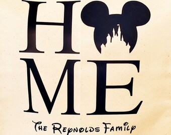 May include: Black and white graphic design with the word "HOME" and a silhouette of Mickey Mouse's head with a castle inside. The text "The Reynolds Family" is below the graphic.