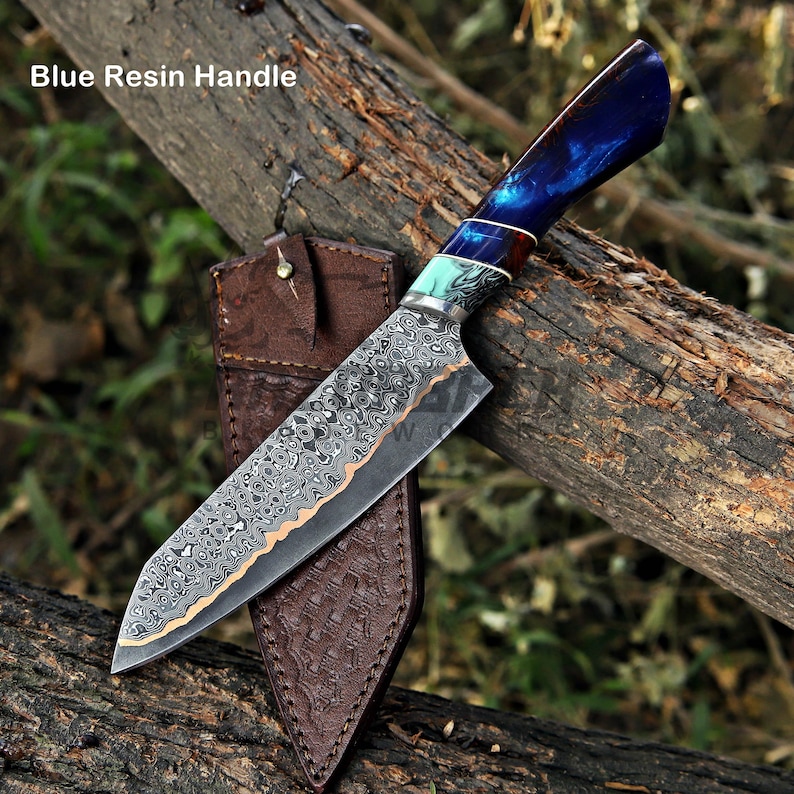 May include: A fixed-blade knife with a patterned Damascus steel blade and a blue resin handle. The handle features a decorative turquoise and silver bolster. The knife is accompanied by a brown leather sheath with a textured, embossed pattern.