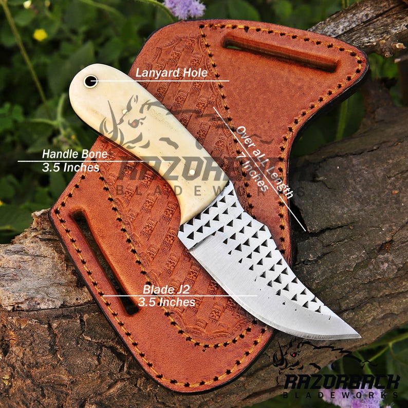 Peut inclure: Un petit couteau &agrave; manche blanc en os et lame dentel&eacute;e, mesurant 17,8 cm de long. Le couteau est dans un fourreau en cuir brun avec un trou pour un cordon. La lame mesure 8,9 cm de long et le manche est en os. Le fourreau porte l'inscription "Razorback Bladeworks".