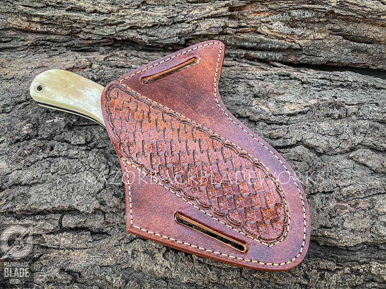 May include: A brown leather knife sheath with a woven pattern and a white handle knife inside. The sheath has a belt loop and a snap closure.