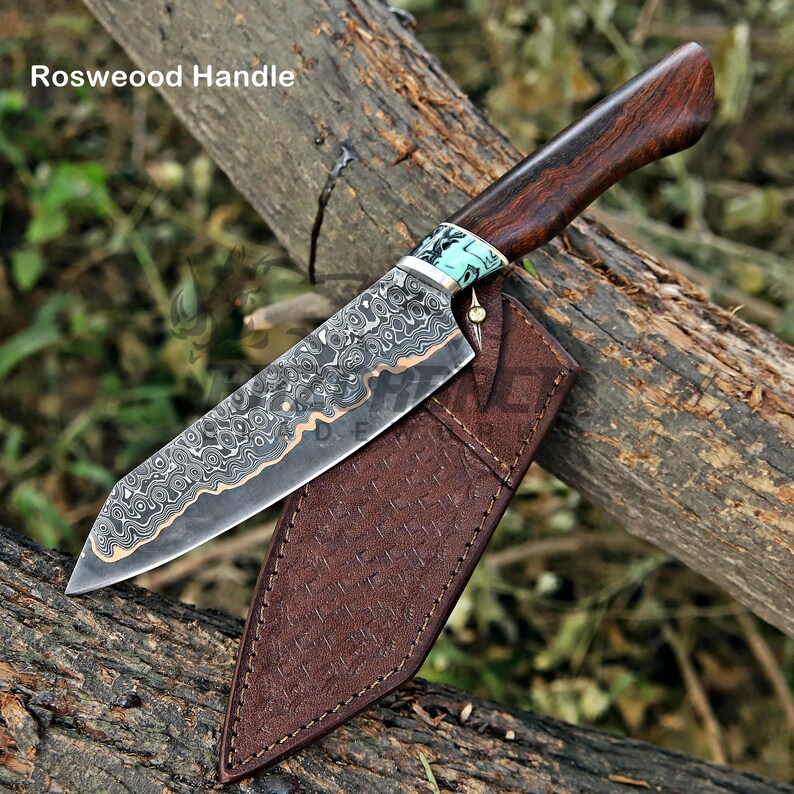 May include: A fixed-blade knife with a patterned Damascus steel blade, a dark brown rosewood handle, and a light blue marbled bolster. The knife includes a brown leather sheath with a textured, cross-hatched pattern and visible stitching.