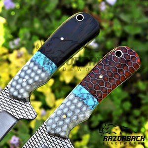K&ouml;nnte beinhalten: Zwei Messergriffe mit einem Materialmix-Design, bestehend aus einem silbernen Wabenmuster, einem Band aus t&uuml;rkisfarbenem Stein und einem dunklen Holz- oder Harzabschnitt. Jeder Griff verf&uuml;gt &uuml;ber einen Metallstift und eine Fangriemen&ouml;se.