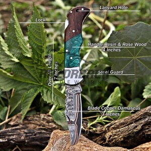 May include: A folding knife with a 3-inch copper Damascus blade, a steel guard, and a 4-inch handle made of rosewood and green resin. The knife features a lock mechanism and a lanyard hole, with an overall length of 7 inches as labeled.