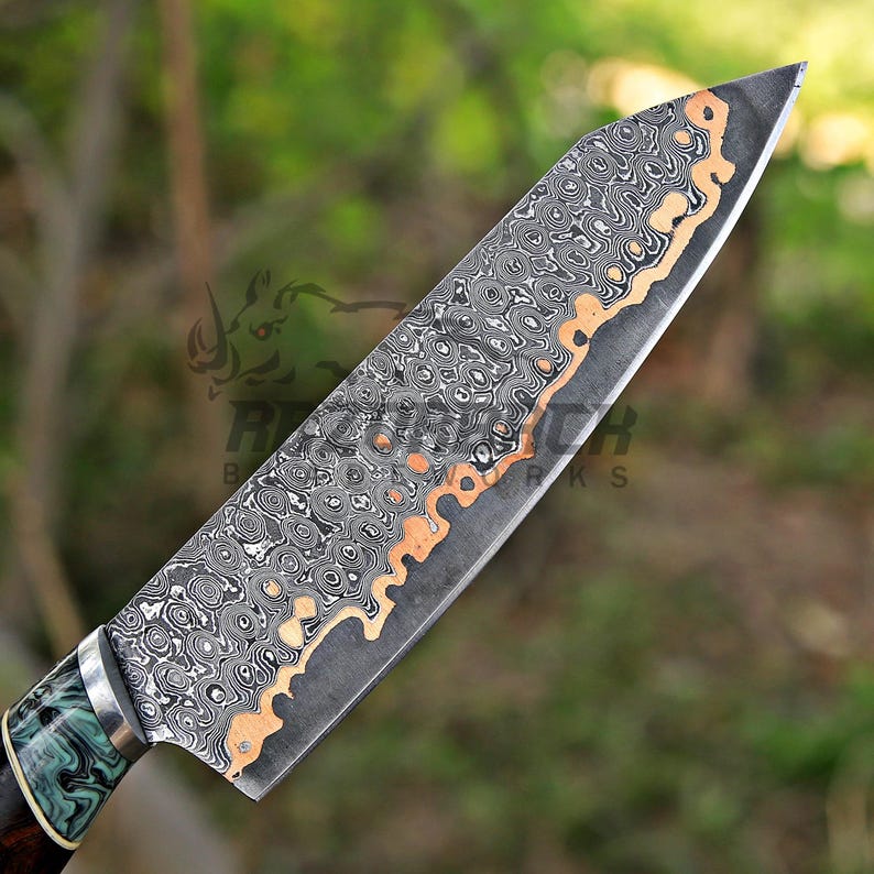 May include: A kitchen knife featuring a blade with a complex, layered Damascus steel pattern in black, gray, and copper tones. The handle is crafted with a marbled green and black resin section, separated from the blade by a silver-colored bolster.