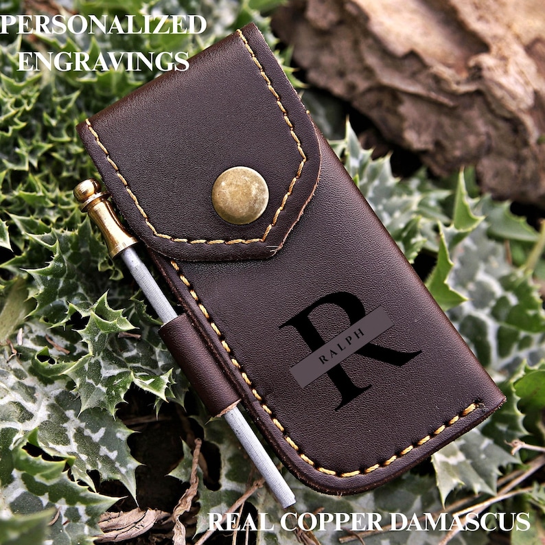 May include: A dark brown leather case with a brass snap button closure and yellow stitching. The case features a black engraved letter R with the name RALPH inside. A small metal tool with a brass-colored top is held in a side loop.