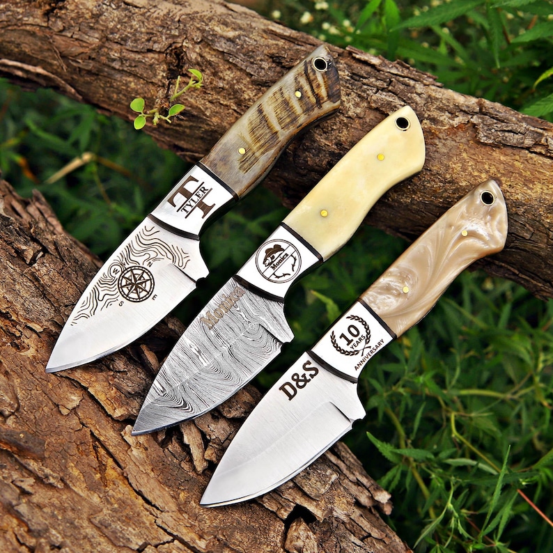 May include: Three fixed-blade knives with distinct handles and engraved blades. The first features a compass and the name Tyler. The second has a Damascus steel pattern and the name Monica. The third displays D&S and 10 Years Anniversary.