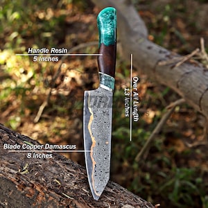 May include: A knife with a copper Damascus steel blade measuring 8 inches, a handle made of wood and teal resin measuring 5 inches, and an overall length of 13 inches. The blade features a distinct wavy pattern and a copper-colored edge.