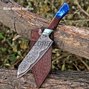 May include: A fixed-blade knife with a patterned Damascus steel blade and a handle made of dark wood and blue resin. The knife is positioned against a brown leather sheath with a textured surface. The text Blue Wood Handle is visible.