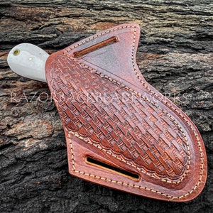 Peut inclure: Un &eacute;tui &agrave; couteau en cuir marron avec un motif tiss&eacute; d&eacute;coratif et des coutures. L'&eacute;tui a une boucle de ceinture et une fermeture &agrave; pression. Le couteau n'est pas inclus.