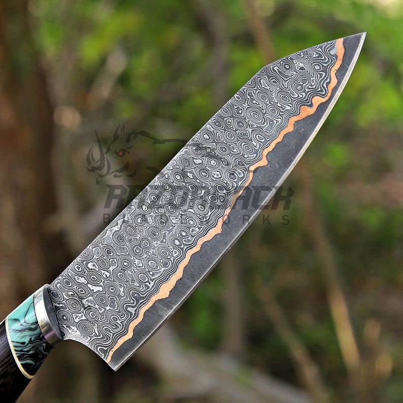 May include: A kitchen knife featuring a Damascus steel blade with a distinct wavy pattern and a copper-colored accent line. The handle is crafted with a marbled green and black material, separated from the blade by a silver-colored metal bolster.