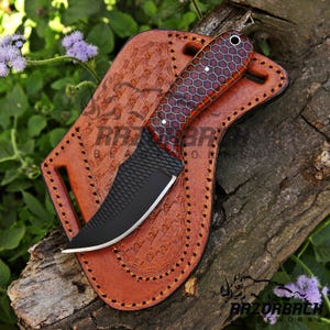 Peut inclure: Un couteau de chasse noir et brun avec une lame textur&eacute;e et un manche &agrave; motif en nid d'abeille. Le couteau est dans un fourreau en cuir brun avec des coutures d&eacute;coratives.