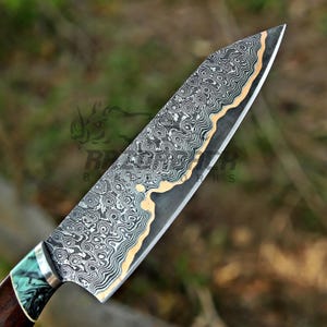 May include: A chef knife featuring a complex Damascus steel blade with a wavy, layered pattern in black, gray, and copper tones. The handle is crafted from dark wood with a marbled teal and black resin bolster, finished with a silver metal ferrule.