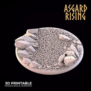 Könnte beinhalten: Eine 3D-druckbare Miniatur-Geländebasis. Die Basis hat eine hellgraue ovale Form mit einer Schottertextur in der Mitte und großen, zerbrochenen Felsformationen an den Rändern. Der Text "ASGARD RISING" ist in goldfarbenen Buchstaben. Der Text "3D PRINTABLE MINIATURES & TERRAINS" befindet sich unten.