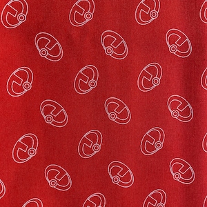 May include: Red fabric with a white repeating pattern of a stylized letter U with a circle inside.
