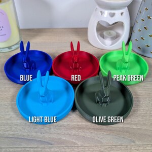 May include: Five ring dishes in different colours: blue, light blue, red, olive green, and peak green. Each dish features a small rabbit figurine.