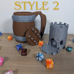 May include: A 3D printed wooden barrel shaped dice tower with a lid and a gray stone tower shaped dice tower with a gray stone base. Both towers are designed to hold dice for tabletop games.