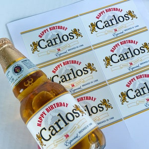May include: A set of six white labels with a gold border and a lion design. The labels say "Happy Birthday Carlos 36 Especial Brewed in 1988".