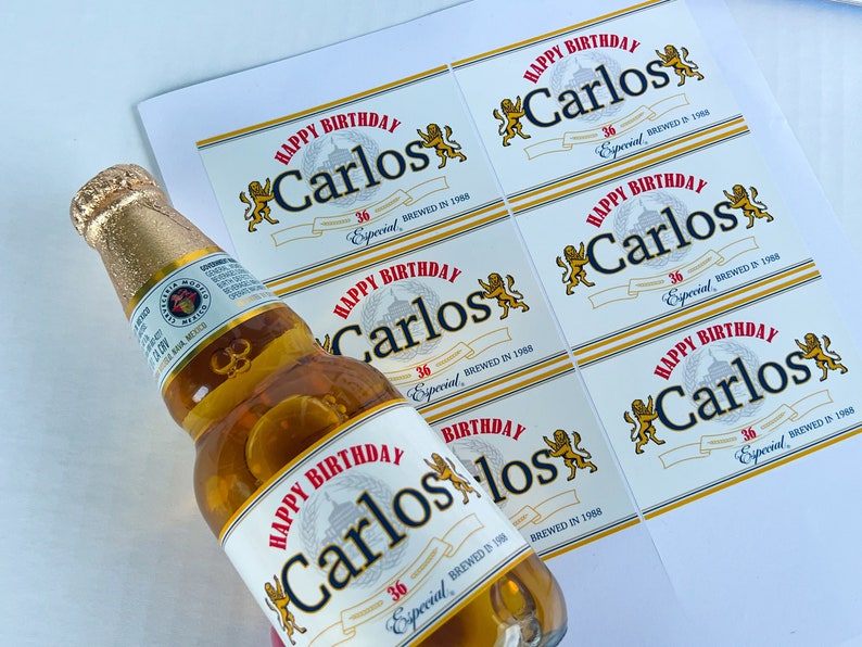 May include: A set of six white labels with a gold border and a lion design. The labels say "Happy Birthday Carlos 36 Especial Brewed in 1988".