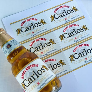 May include: A set of six white labels with a gold border and a red and gold design. The labels feature the text "Happy Birthday Carlos" with the year "1988" and the words "36 Especial" printed on them. The labels are designed to be placed on beer bottles.