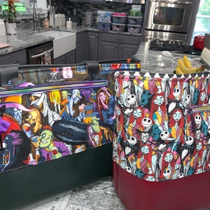 May include: Two tote bags with a green and red base and a colorful print of characters from the Nightmare Before Christmas movie. The bags have a zipper and a top handle.