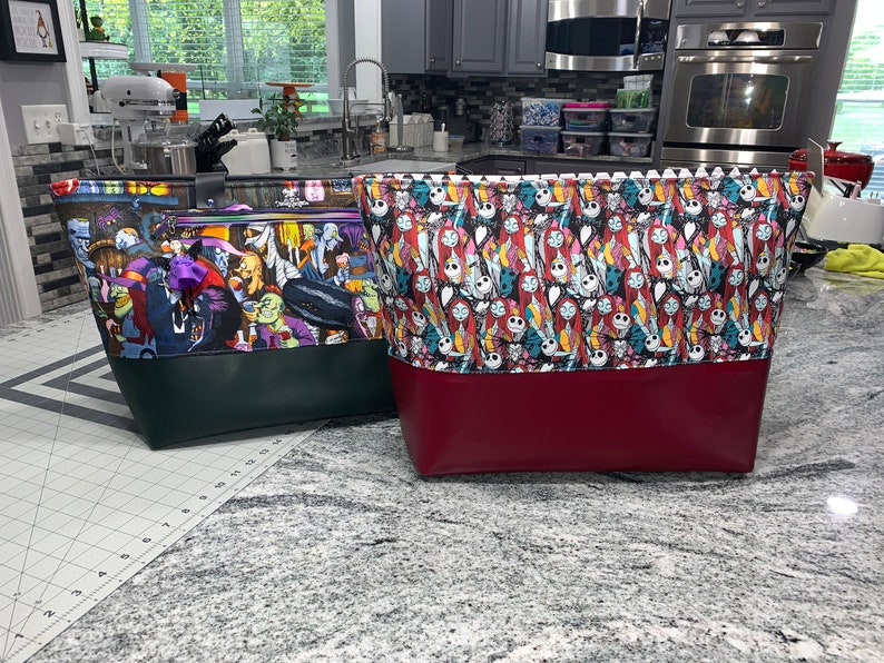 May include: Two large tote bags with colorful fabric designs. The bag on the left has a green and black design with a scene of characters from a movie. The bag on the right has a red and black design with a pattern of faces from a movie. Both bags have a solid colored bottom.