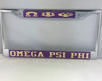 May include: A chrome license plate frame with a purple background and gold lettering that reads "Omega Psi Phi".