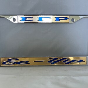 May include: A chrome license plate frame with a gold and blue Sigma Gamma Rho sorority emblem and the text "Ee-Yip" in blue on a gold background.