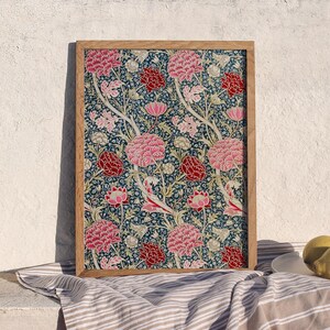 May include: A framed print of a floral pattern with pink, red, and white flowers on a dark blue background.