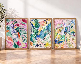 May include: Three rectangular framed wall art prints featuring vibrant, abstract landscape paintings with expressive brushstrokes in shades of green, blue, yellow, pink, and red. Each print is encased in a light-toned wooden frame.