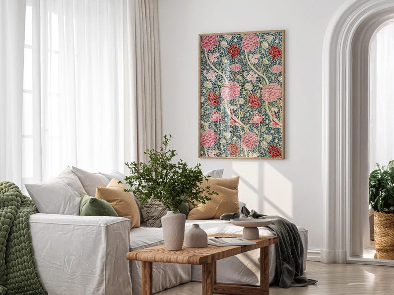 May include: A white sofa with green and beige cushions, a green throw blanket, and a wooden coffee table. A potted plant sits on the table, and a framed floral print hangs on the wall behind the sofa.