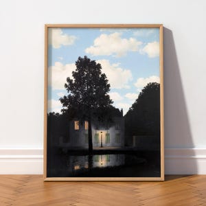 Peut inclure: Une impression d'art encadrée représentant une maison sombre la nuit avec un réverbère allumé devant, la silhouette d'un grand arbre et un reflet dans une mare, le tout sous un ciel bleu clair parsemé de nuages blancs en plein jour.