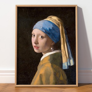 May include: A framed print of Johannes Vermeer's "Girl with a Pearl Earring." The portrait features a young person with a pearl earring, wearing a blue and yellow headscarf and a mustard-colored jacket against a dark background.