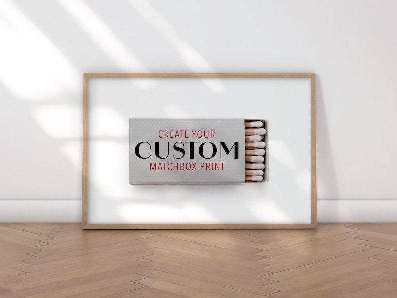 K&ouml;nnte beinhalten: Gerahmter Druck mit Streichholzschachtel-Design. Die Streichholzschachtel ist ge&ouml;ffnet und zeigt Streichh&ouml;lzer. Der Text "CREATE YOUR CUSTOM MATCHBOX PRINT" ist in Schwarz und Rot dargestellt. Der Rahmen ist hellbraun.