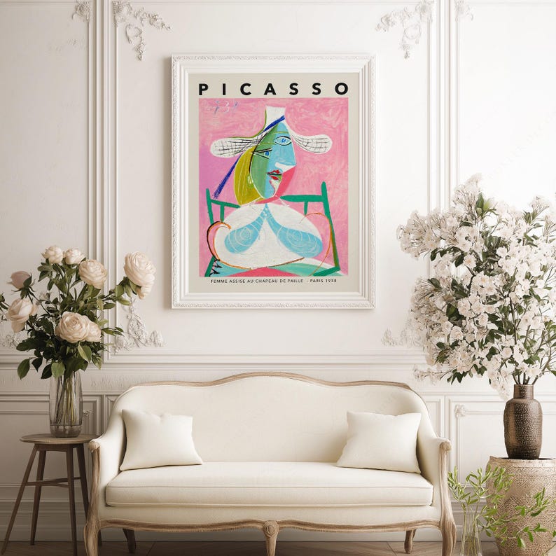 May include: A framed art print titled PICASSO featuring the painting Femme assise au chapeau de paille. The artwork displays a stylized figure in a wide-brimmed hat with blue, green, and yellow tones against a textured pink background.
