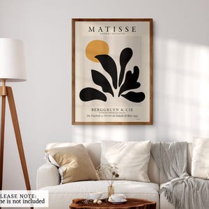 May include: A rectangular wall art print featuring a Matisse Papiers D&eacute;coup&eacute;s exhibition poster. The design includes a yellow circle above abstract black organic shapes on a cream background, with text reading MATISSE, BERGGRUEN & CIE.
