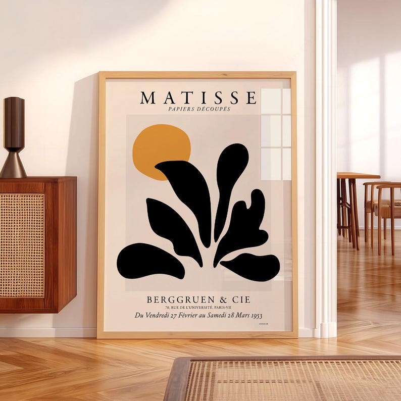 May include: A framed Matisse Papiers D&eacute;coup&eacute;s exhibition poster featuring a yellow circle and black organic shapes on a light background. The text reads MATISSE PAPIERS D&Eacute;COUP&Eacute;S, BERGGRUEN & CIE, 70, RUE DE L'UNIVERSIT&Eacute;, PARIS-VII, Du Vendredi 27 F&eacute;vrier au Samedi 28 Mars 1953.