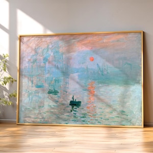 May include: A rectangular framed wall art print featuring an impressionist painting of a harbour at sunrise. The scene depicts a small boat on water with a bright orange sun reflecting on the surface, surrounded by soft blue and pink hazy tones.