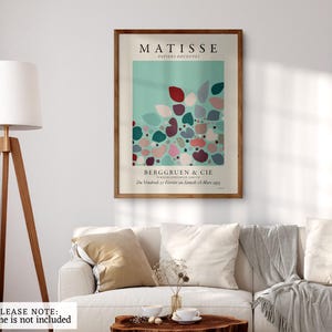 May include: A vintage poster for an art exhibition featuring a colorful abstract design of cut paper shapes in shades of pink, red, green, and blue on a light blue background. The poster is titled "Matisse, Papiers Decoupes" and includes the text "Berggruen & Cie (Du Vendredi 17 Fevrier au Samedi 11 Mars 1955)".