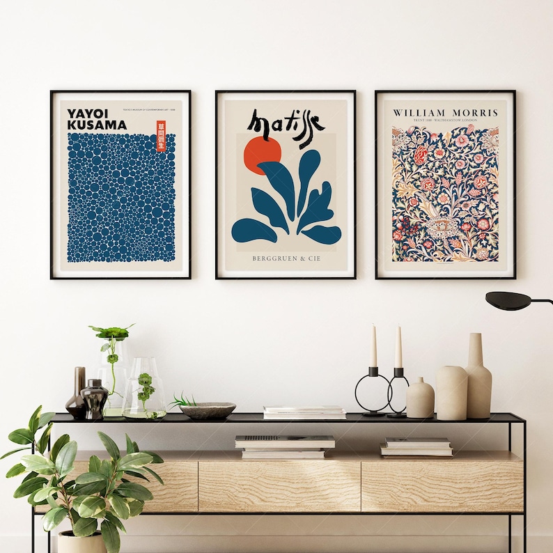 May include: Three framed art prints with minimalist designs. The left print features a blue and white pattern of circles with the text "Yayoi Kusama". The middle print features a blue and red abstract design with the text "matisse" and "Berggruen & Cie". The right print features a floral pattern with the text "William Morris".
