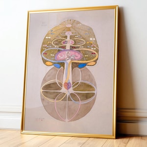 May include: A framed abstract artwork with a gold frame. The artwork features a complex, symmetrical design with a central vertical axis. The color palette includes gold, pink, blue, and brown tones, creating a visually intricate composition.