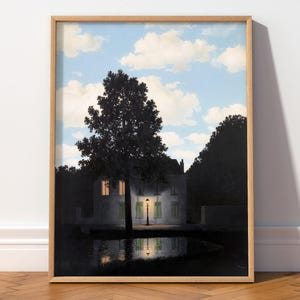 May include: A framed art print depicting a surreal landscape with a dark tree in the foreground, a house illuminated by a single street lamp, and a reflection in a pool of water, all set against a bright blue sky filled with white clouds.