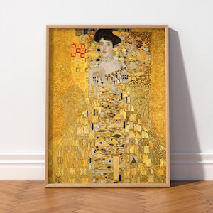 May include: A framed art print featuring a portrait of a person with dark hair, wearing a gown adorned with intricate gold, yellow, and brown geometric patterns. The background is a textured, shimmering gold surface with various abstract shapes.