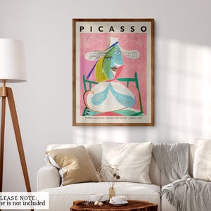 Modern abstract art featuring a striking figure with a large white hat, set against a vibrant pink background that evokes a sense of warmth and playfulness. The subject's face is characterized by angular shapes, bold outlines, and a mix of cool blues and greens, creating a dynamic contrast. The composition balances simplicity and complexity, with geometric elements and a whimsical expression. 'Femme 1938' by Picasso framed and displayed on a minimalist office wall. Printed poster wall art.