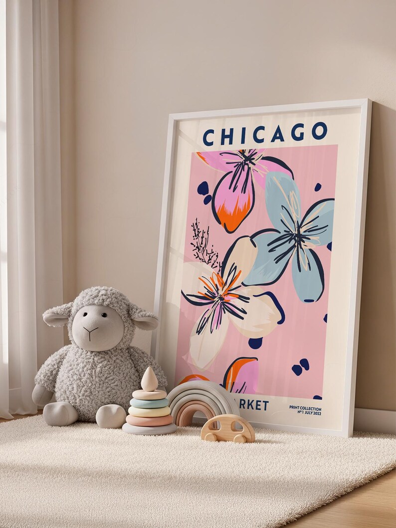 May include: A framed wall art print featuring the text CHICAGO and MARKET with a floral illustration in pink, blue, and orange. The print includes the text PRINT COLLECTION N&deg;1 JULY 2022. The artwork is displayed in a white frame.