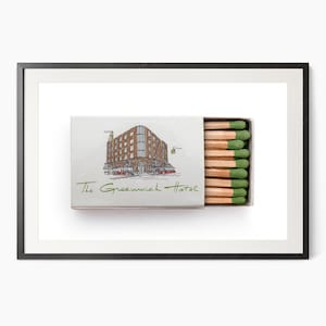 K&ouml;nnte beinhalten: Gerahmter Druck einer ge&ouml;ffneten Streichholzschachtel mit einer Geb&auml;udeillustration und dem Text "The Greenwich Hotel". Die Streichh&ouml;lzer haben gr&uuml;ne K&ouml;pfe. Das Kunstwerk ist vor einem wei&szlig;en Hintergrund.