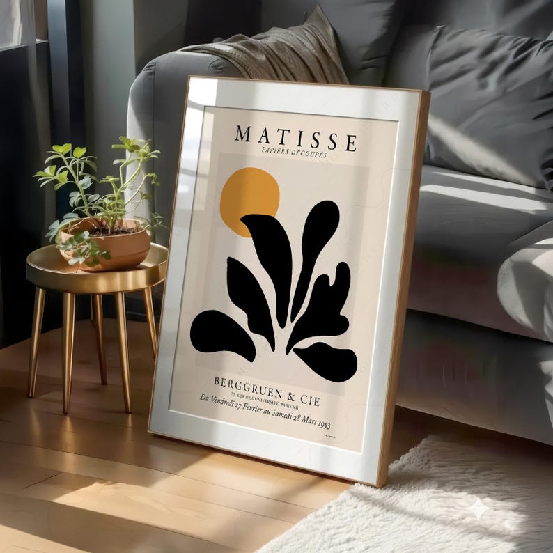May include: A framed art print featuring a Matisse Papiers D&eacute;coup&eacute;s exhibition poster with a yellow circle and black organic leaf shapes on a beige background, with text reading Matisse, Papiers D&eacute;coup&eacute;s, and Berggruen & Cie, 70 Rue de l'Universit&eacute;, Paris VII.