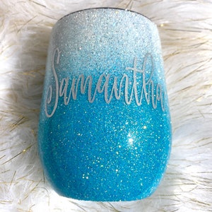May include: A blue and white ombre glitter tumbler with the name "Samantha" written in silver lettering.